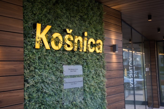 Exterior entrance of Košnica Beehive in Novi Pazar — yellow KOŠNICA letters on a living green wall